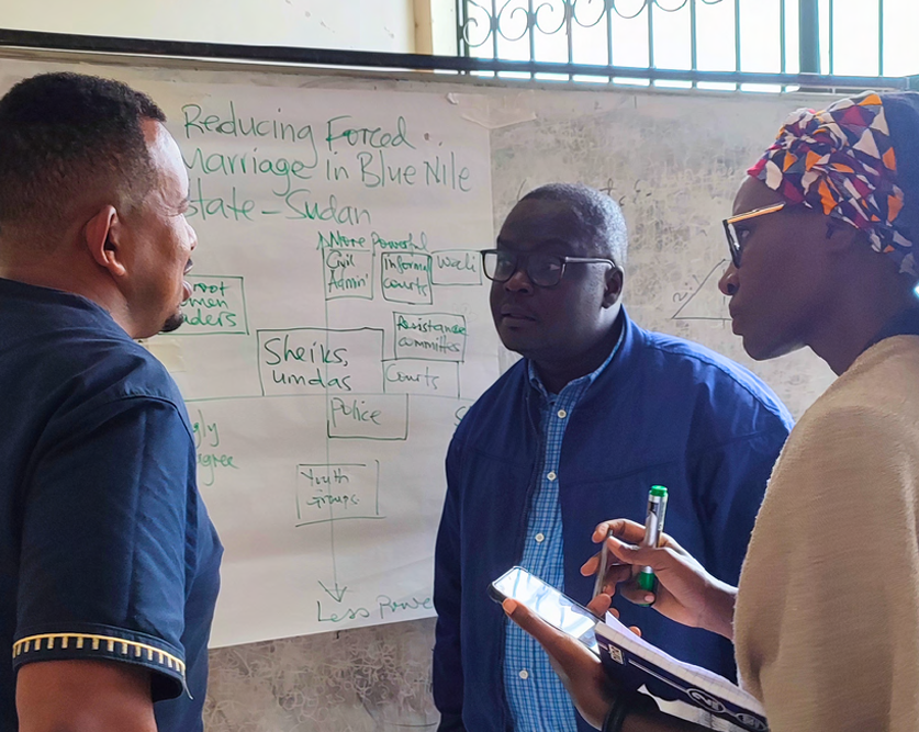 Three people standing next to a flip chart with notes at an LSE workshop