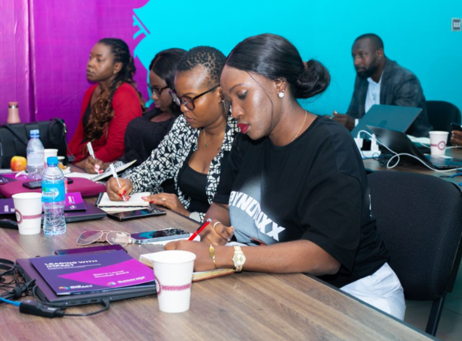 People seated behind a desk writing notes at an LSE training session