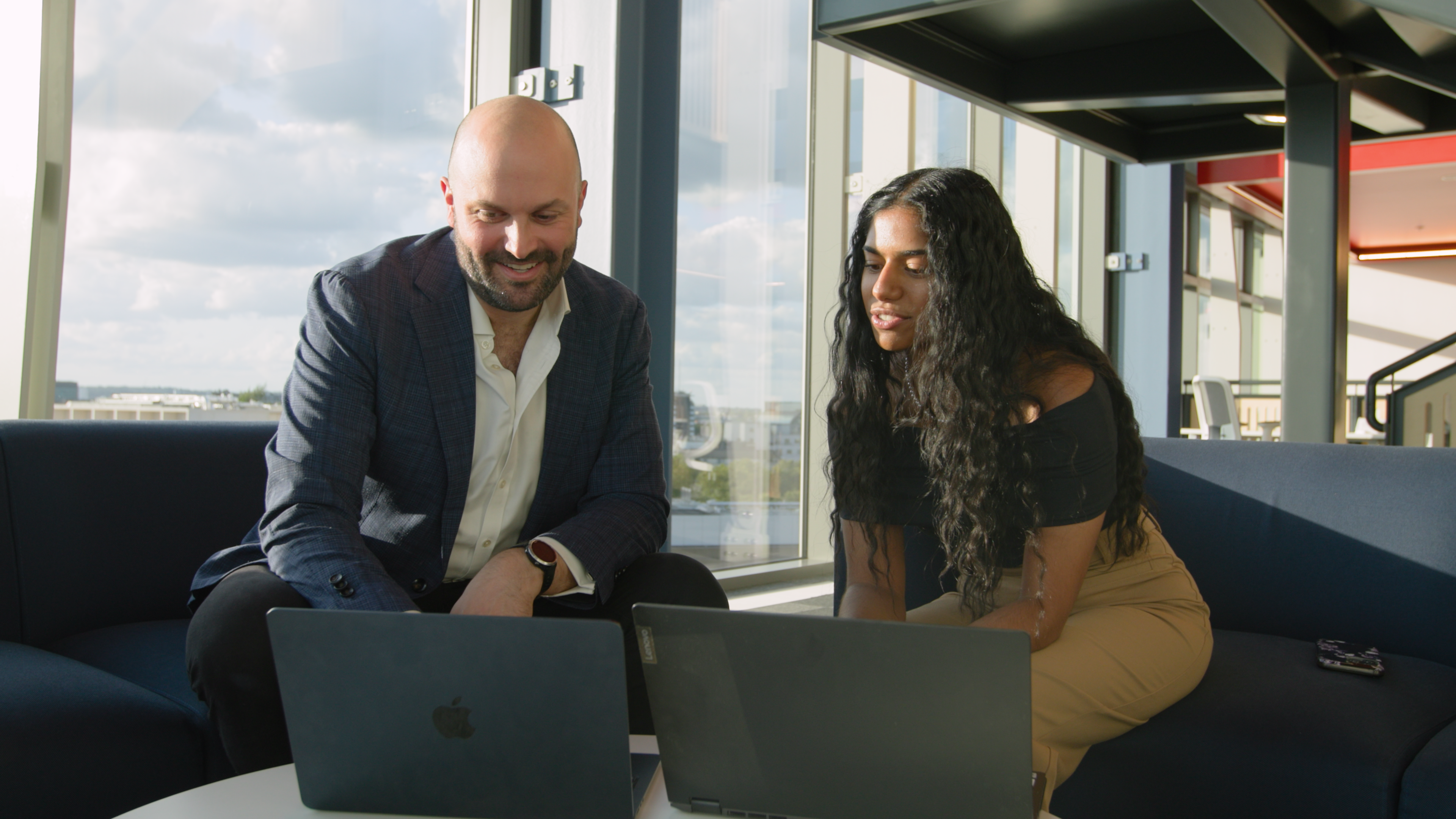 LSE alumni Hanya Pillai and Michael Martin woking together on laptop computers.